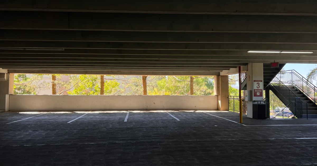Empty parking area with several vacant spaces and trees visible.
