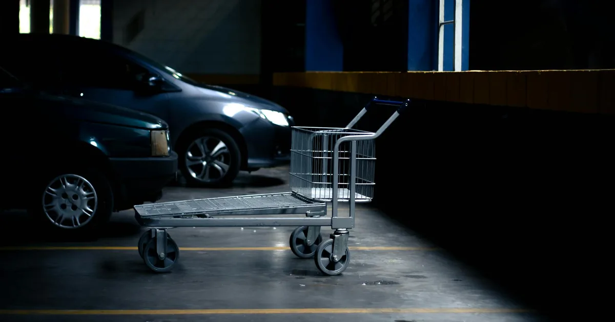 Empty parking space with a shopping cart in a dimly lit garage.