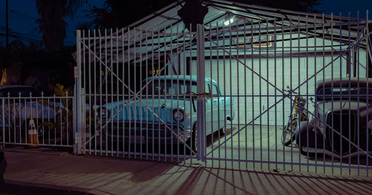 Gated parking space with a vintage car and a motorcycle inside.