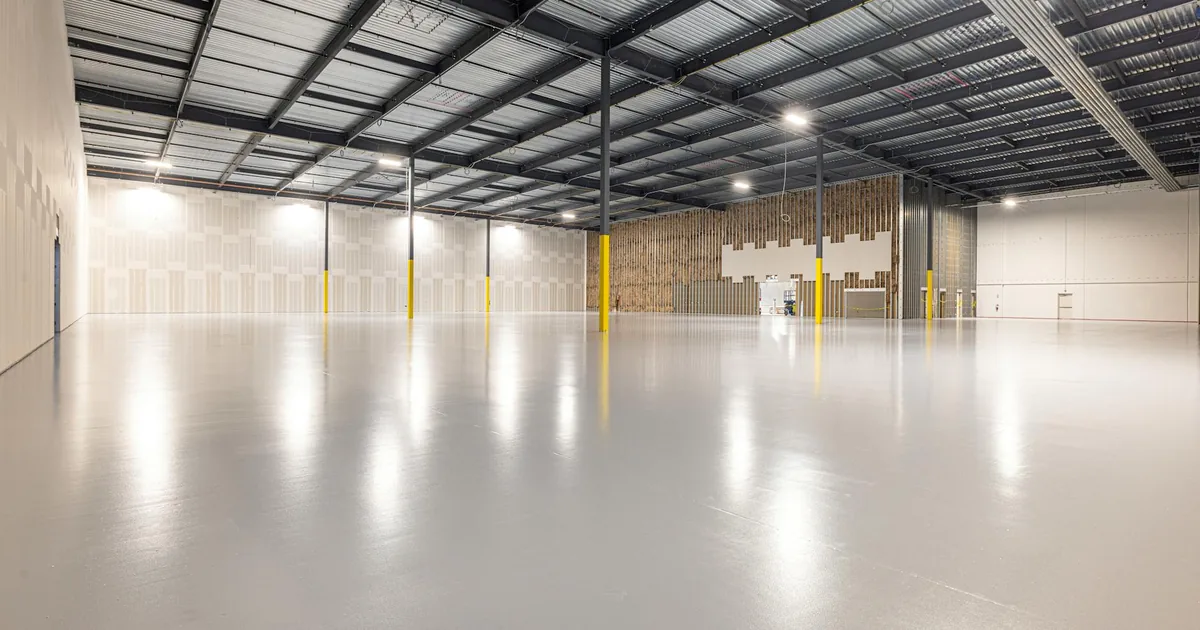 Large empty indoor parking space with smooth flooring and bright.