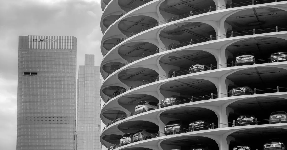 Multi level parking garage with parked cars and a city skyline in.