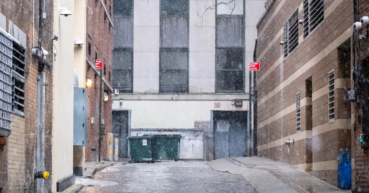Narrow alley with parking signs a dumpster and wet pavement in a.