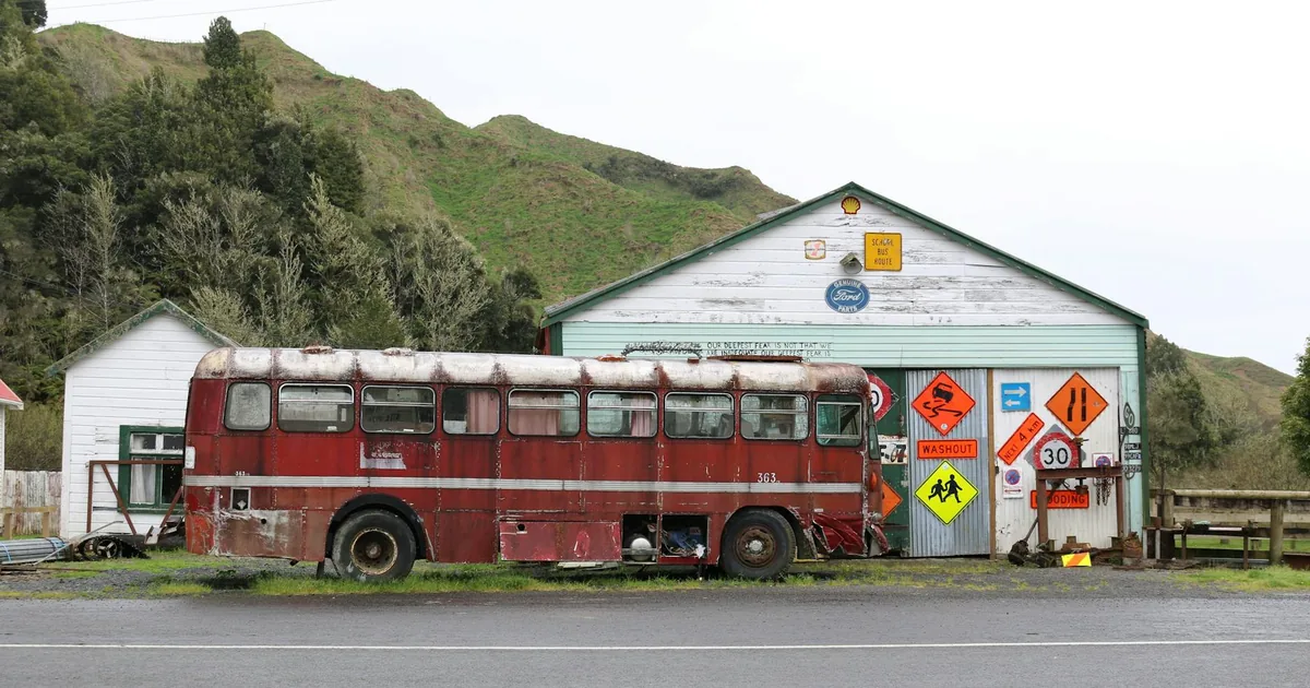 Old bus parked beside a weathered building with various warning.
