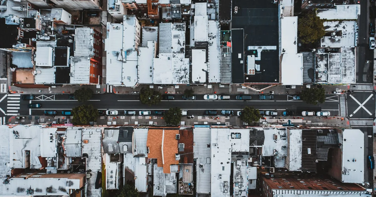 Overhead view of a street lined with parked cars and buildings in.