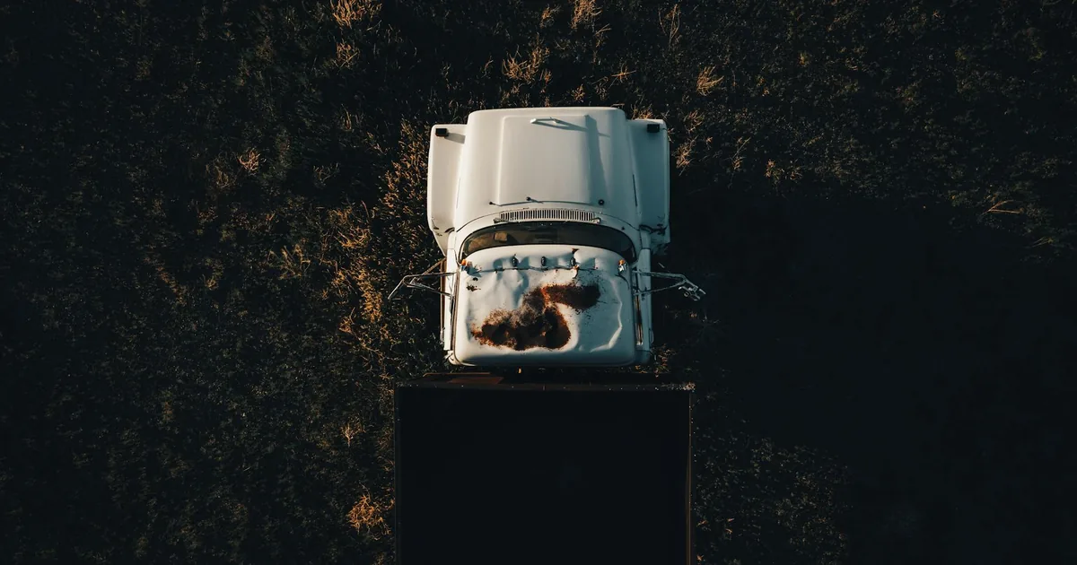 Overhead view of a white vehicle parked on grass with some snow on.