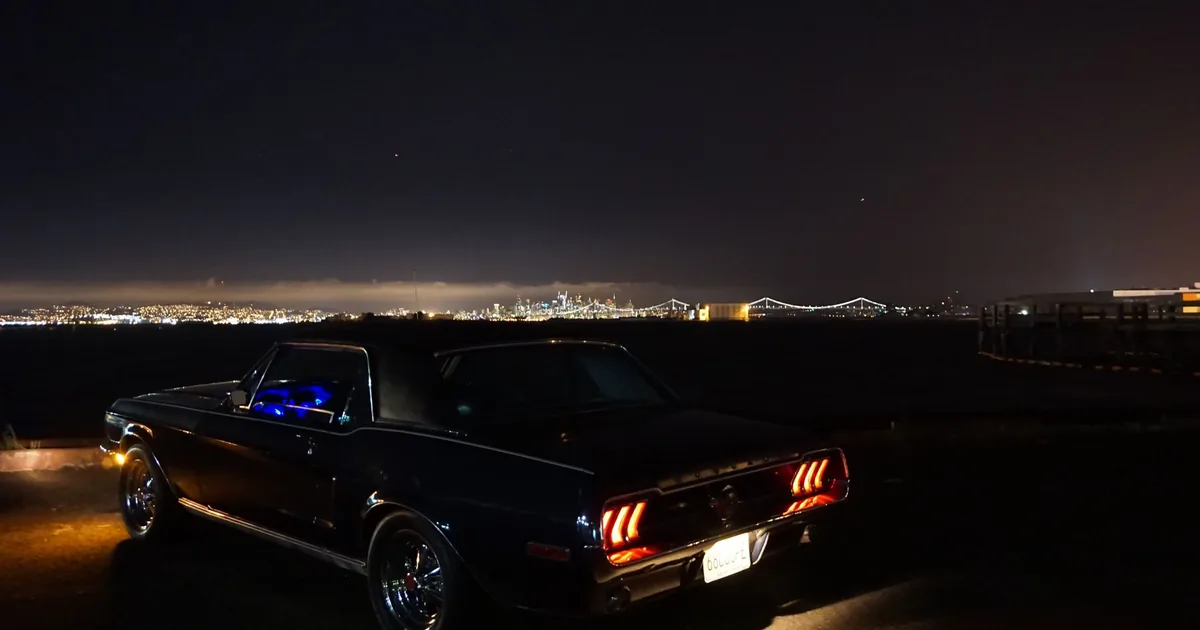 Parked car by the waterfront at night with city lights in the.