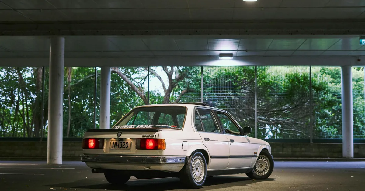 Parked car in a dimly lit garage with greenery visible outside.