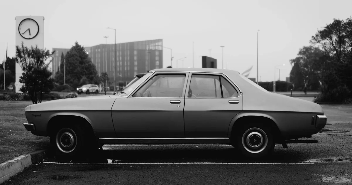Parked car in a parking lot with a clock tower and buildings in the.