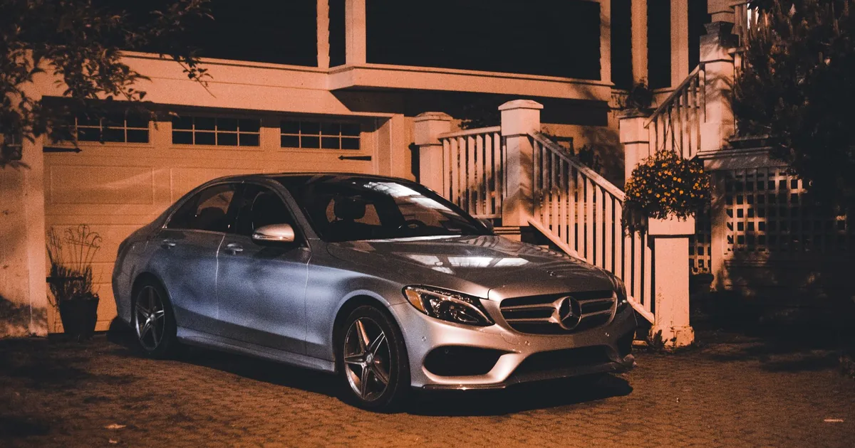 Parked car in front of a house at night with soft lighting.