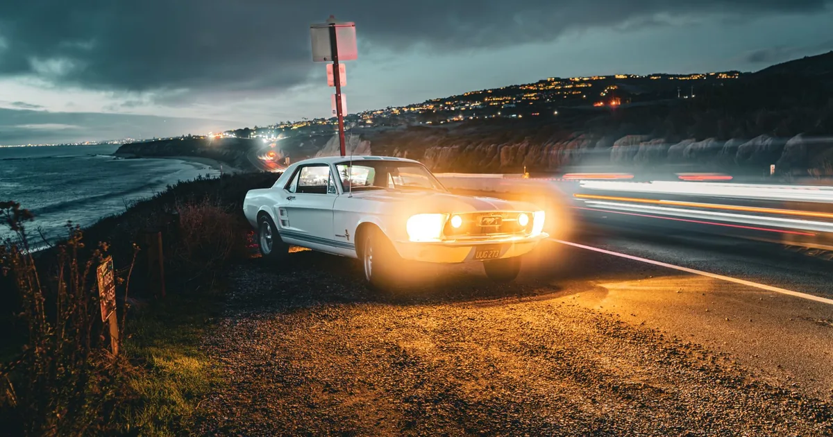 Parked car on a coastal road with ocean view and city lights in the.