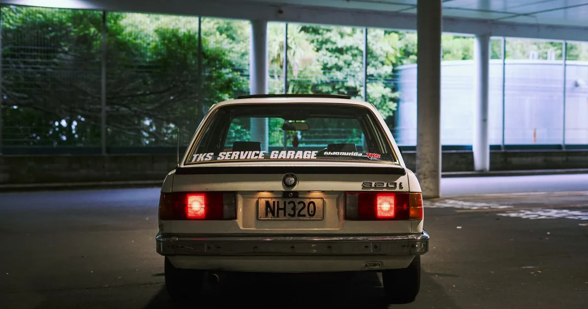 Parked vehicle in a dimly lit parking area with greenery in the.