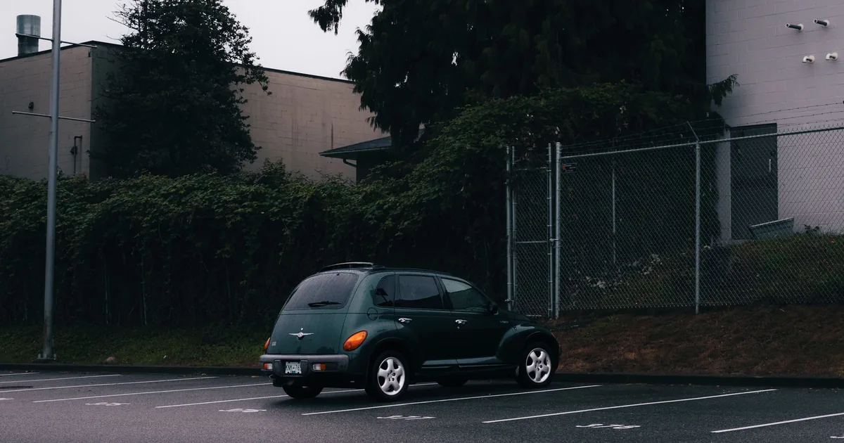 Parked vehicle in an empty parking lot surrounded by greenery.