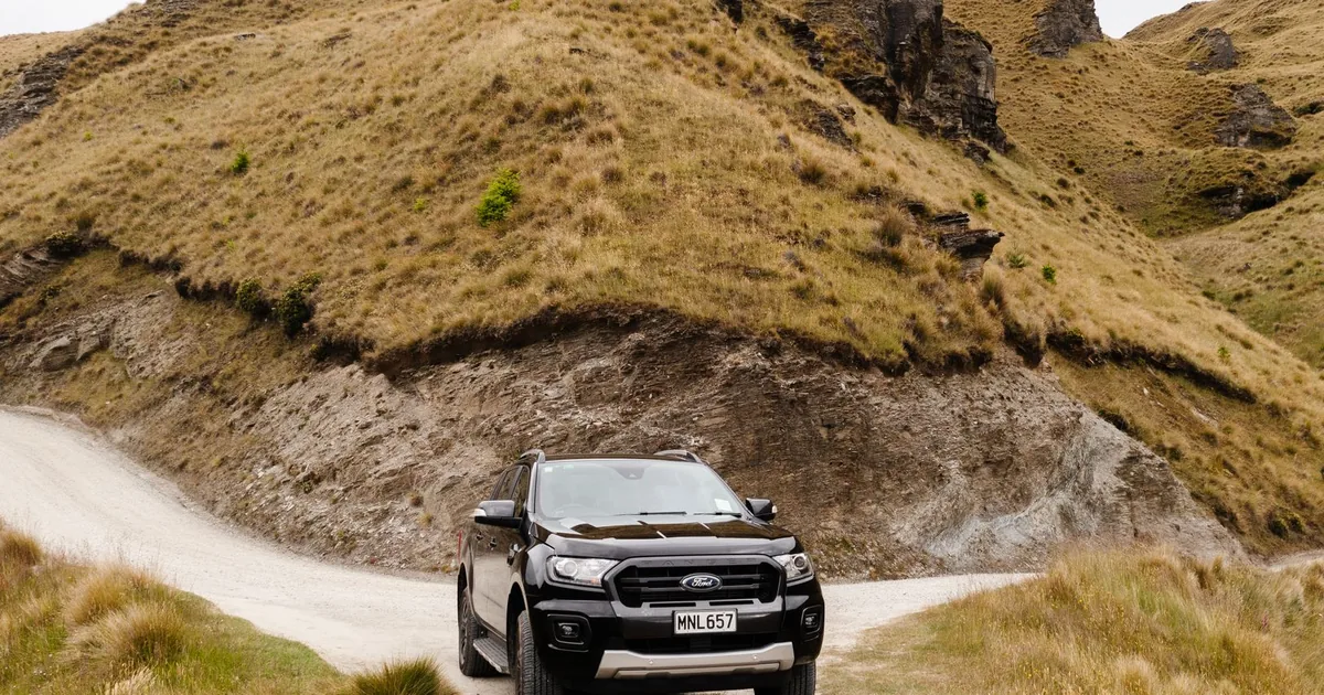 Parked vehicle on a gravel road with a grassy hillside in the.