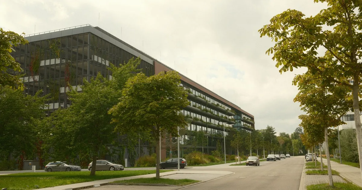 Parking area beside a modern building with trees and a street view.