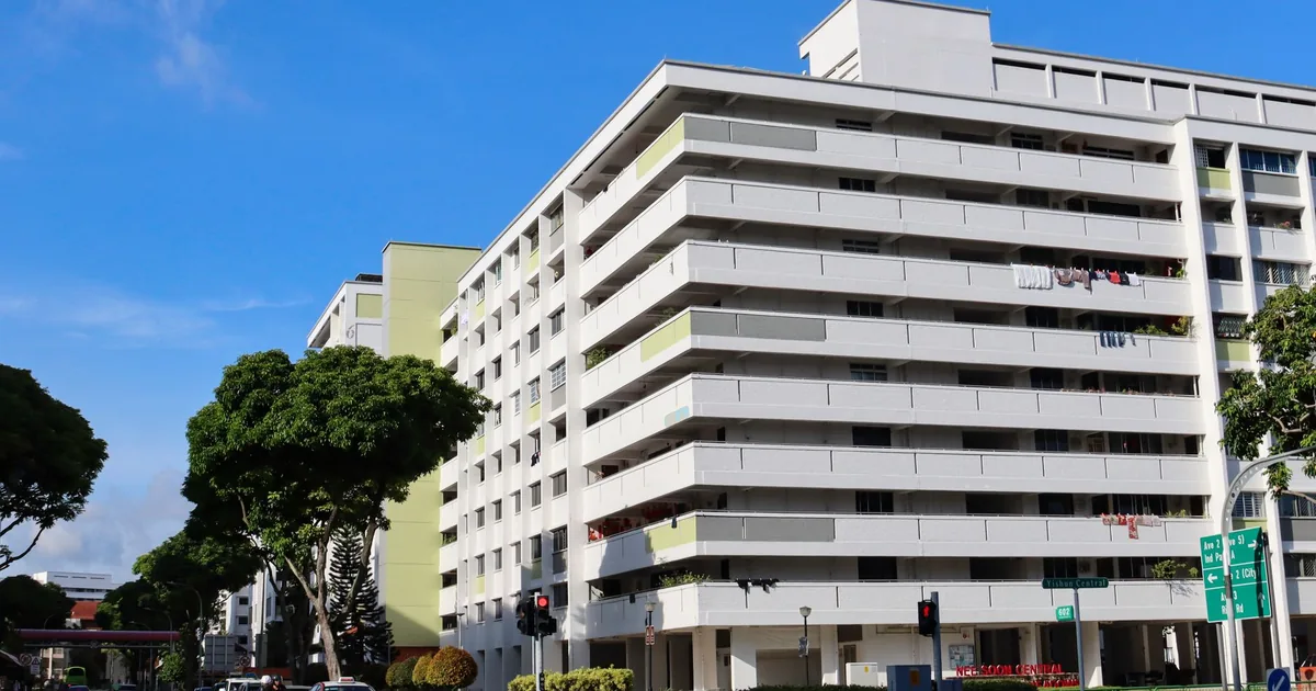 Parking area beside a residential building with trees and clear.
