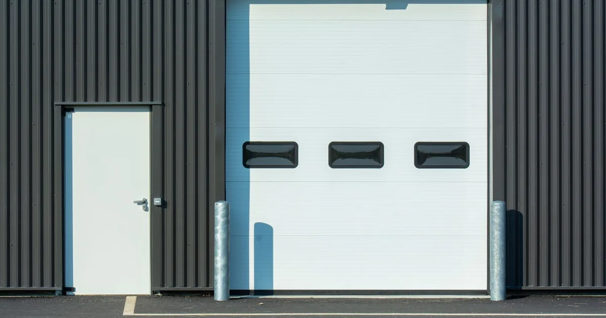 Parking area featuring a garage door and a side door with metal.