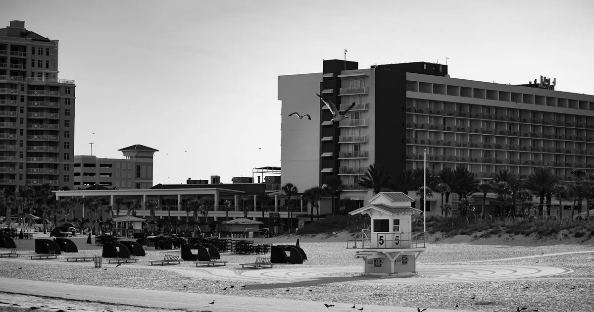 Parking area near the beach with lounge chairs and lifeguard tower.