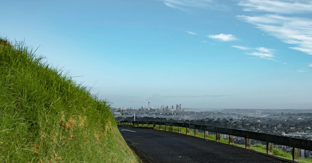 Parking area with a view of a city skyline and green grass on the.