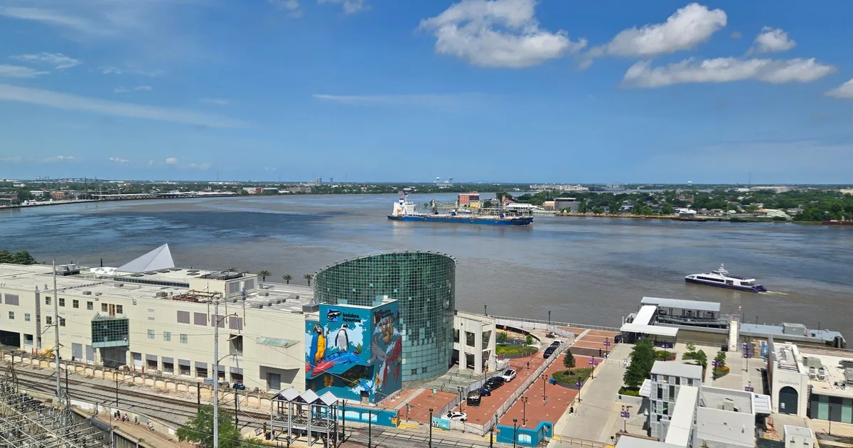Parking area with buildings and a river view under a clear blue sky.