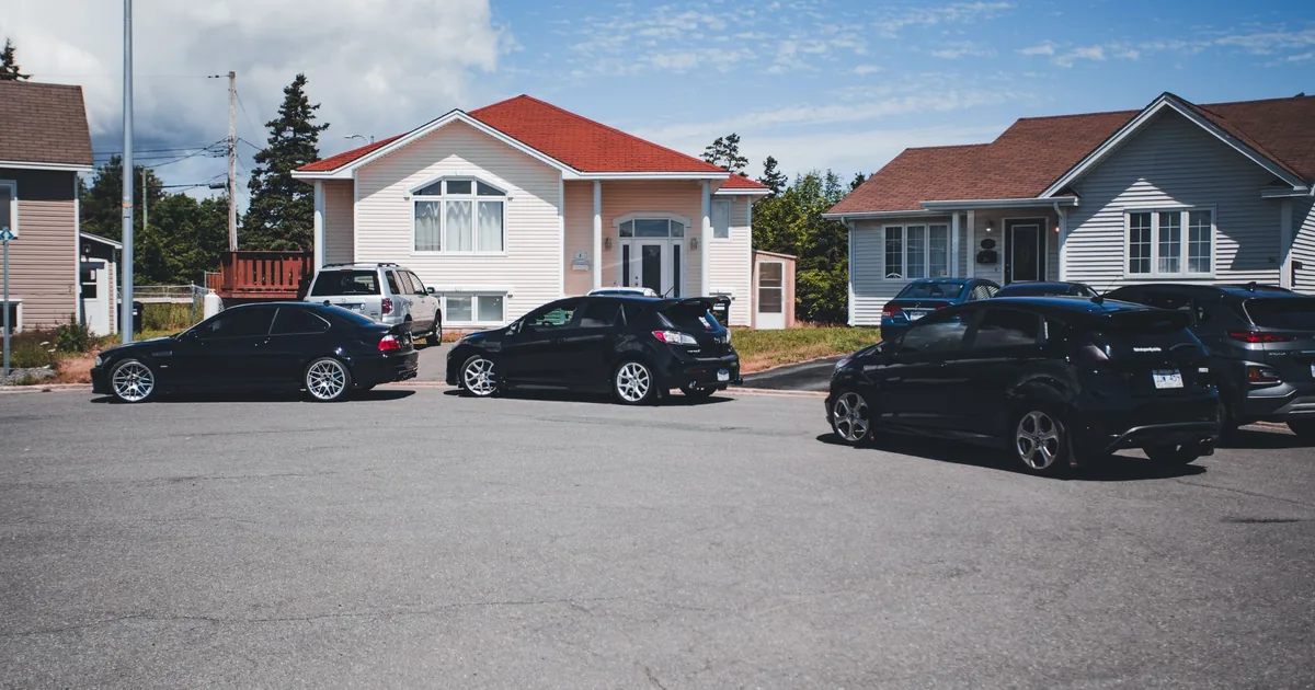 Parking area with several cars near residential houses under a blue.