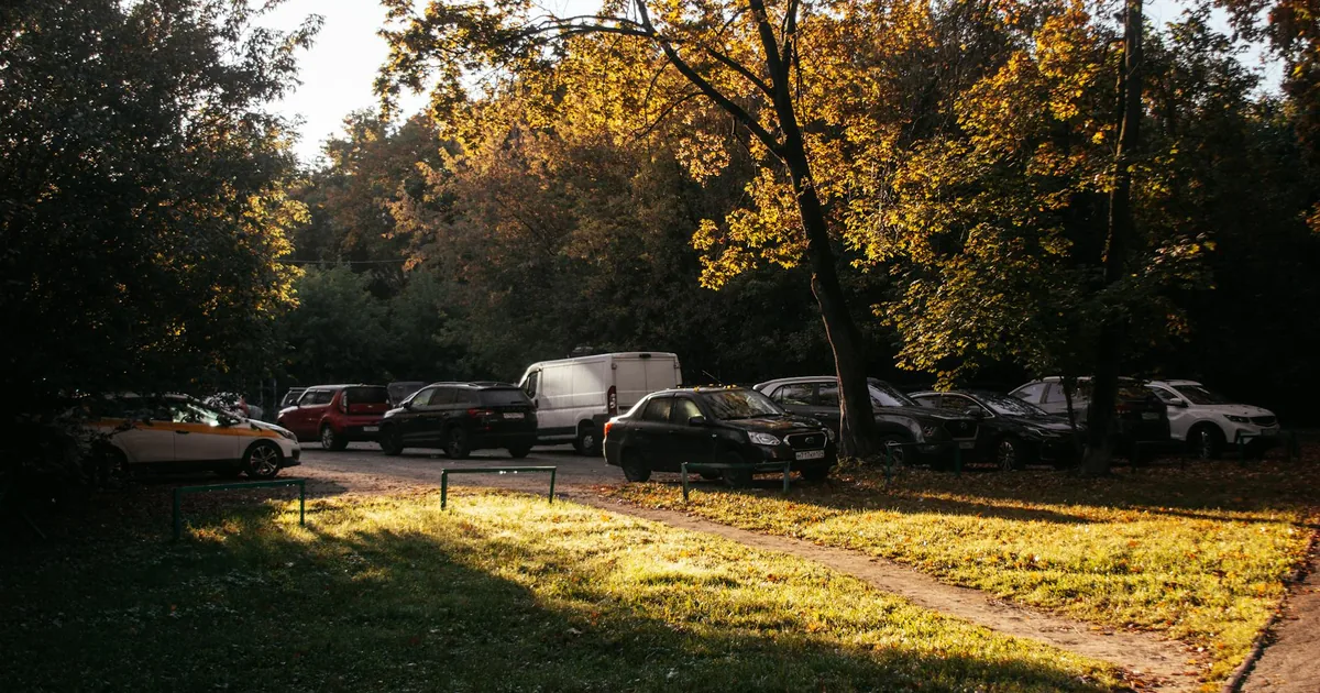 Parking area with several cars surrounded by trees and autumn.