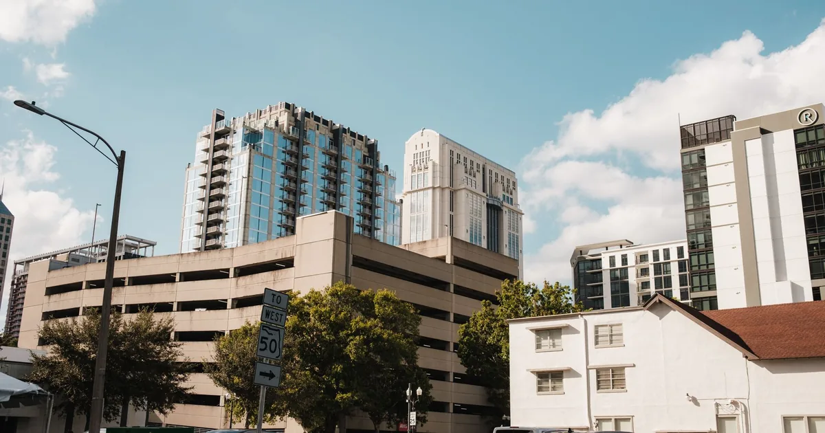 Parking garage surrounded by modern buildings under a blue sky.