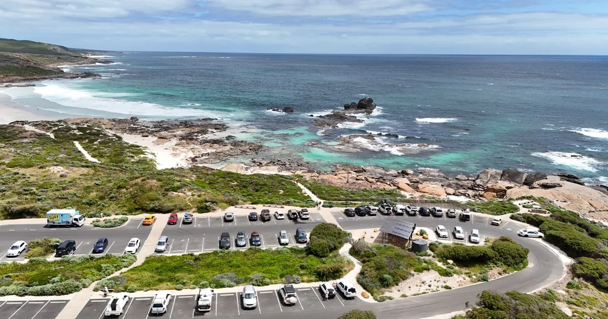 Parking lot near the coast with cars and a scenic ocean view.