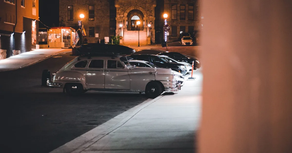 Parking lot scene featuring multiple cars including a vintage.
