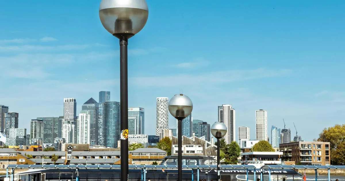 Parking lot with street lamps and a city skyline in the background.