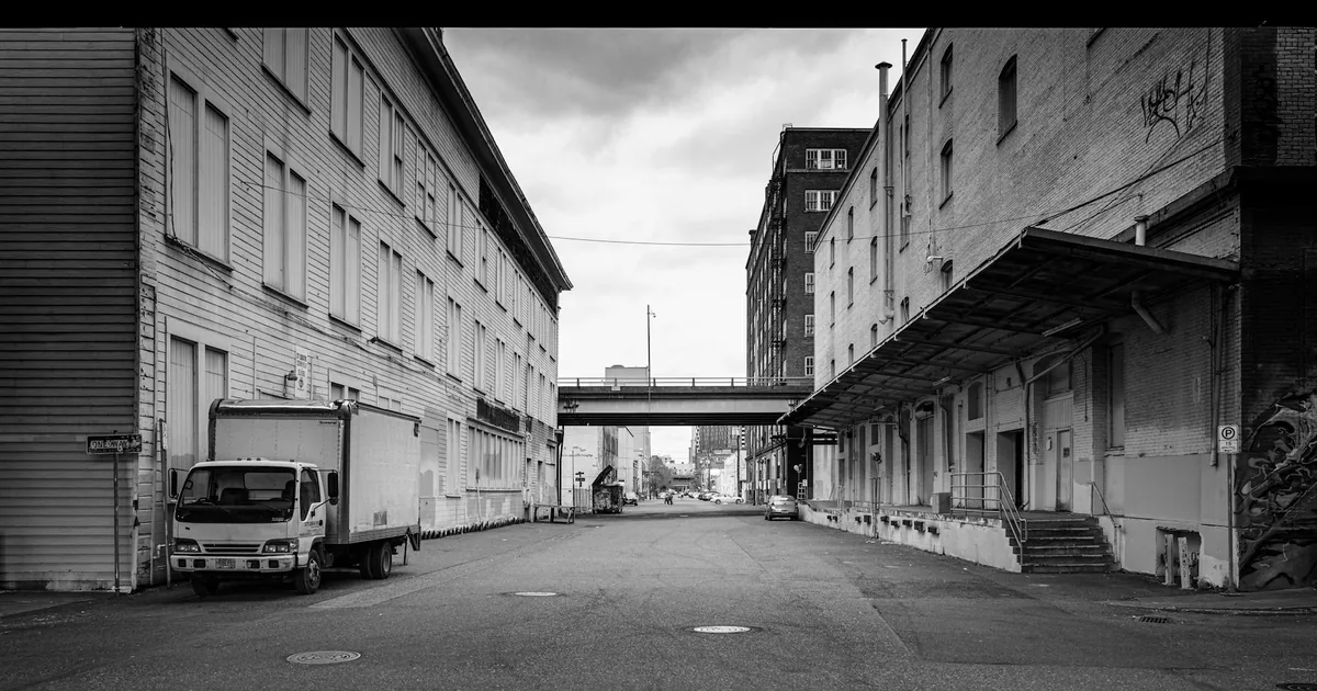 Parking scene featuring a street with buildings and a truck.