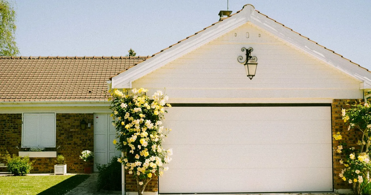 Parking space in front of a house with flowers and a garage door.