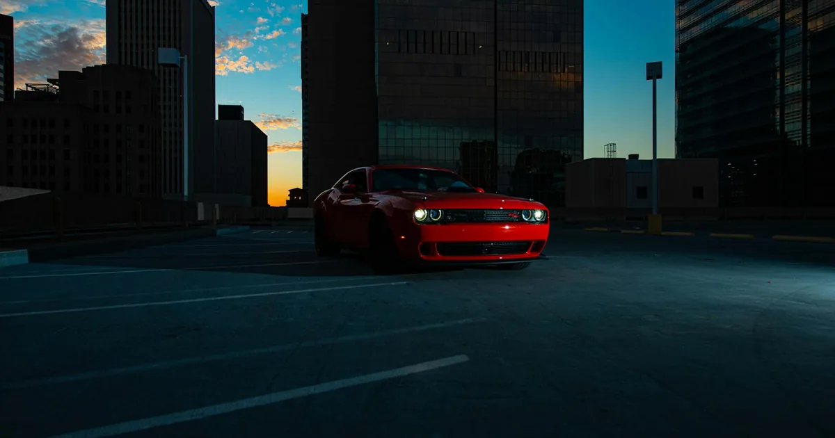 Red car parked in an empty urban parking lot during sunset.