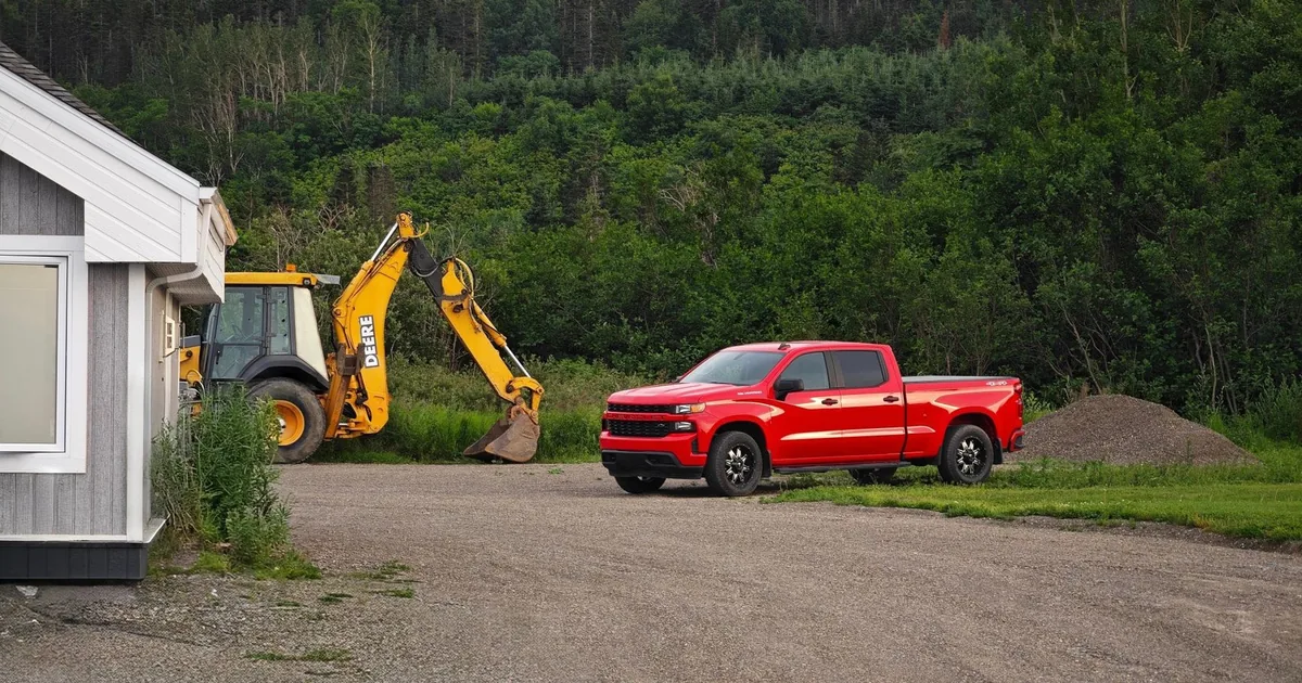 Red pickup truck parked near a construction site with a backhoe.
