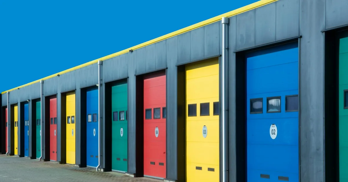 Row of colorful garage doors in various shades set against a clear.