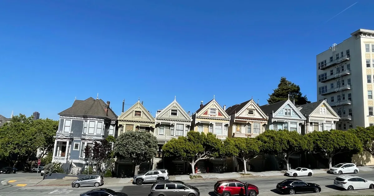 Row of colorful houses with several parked cars along the street.