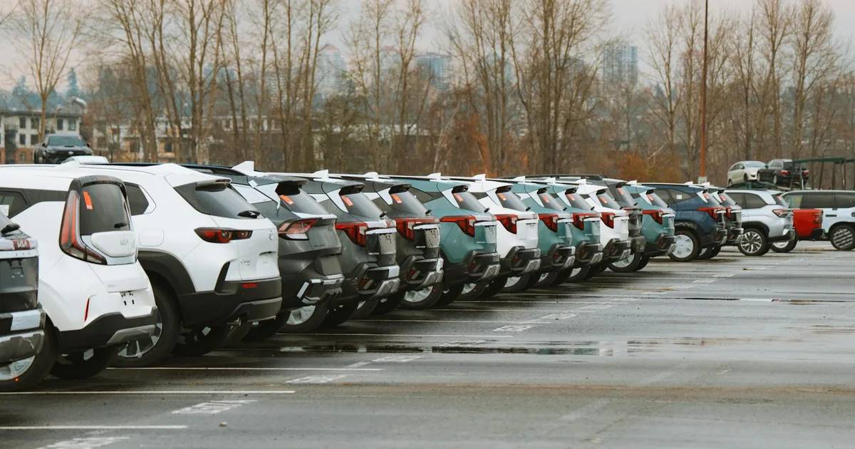 Row of various parked vehicles in a parking lot with trees in the.
