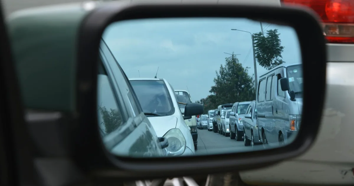 Side mirror view of parked cars in a busy parking lot with cloudy.