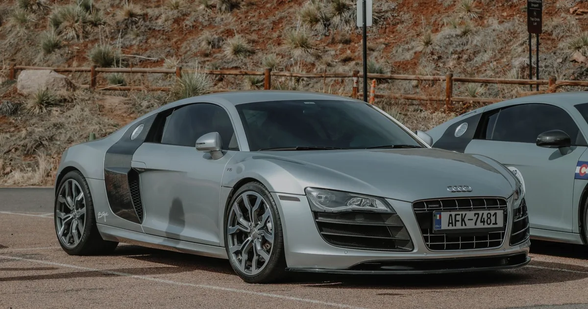 Silver sports car parked in a lot with a natural background.