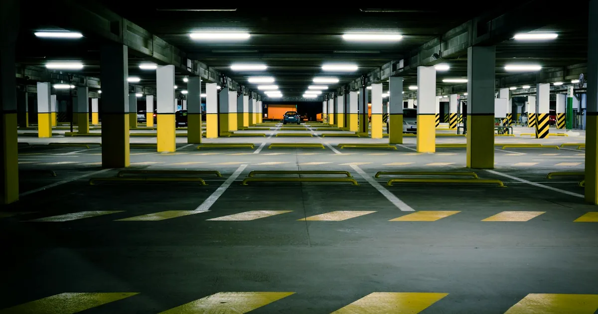 Spacious underground parking with yellow stripes and few parked cars.
