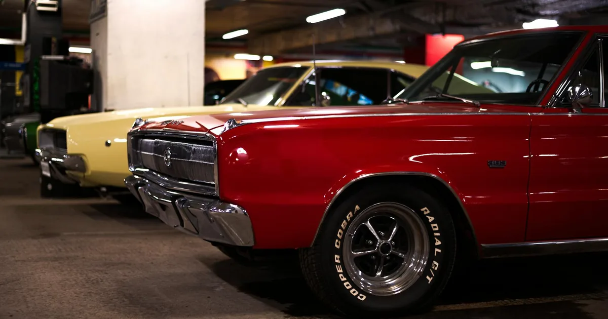 Three classic cars parked in a dimly lit underground parking garage.