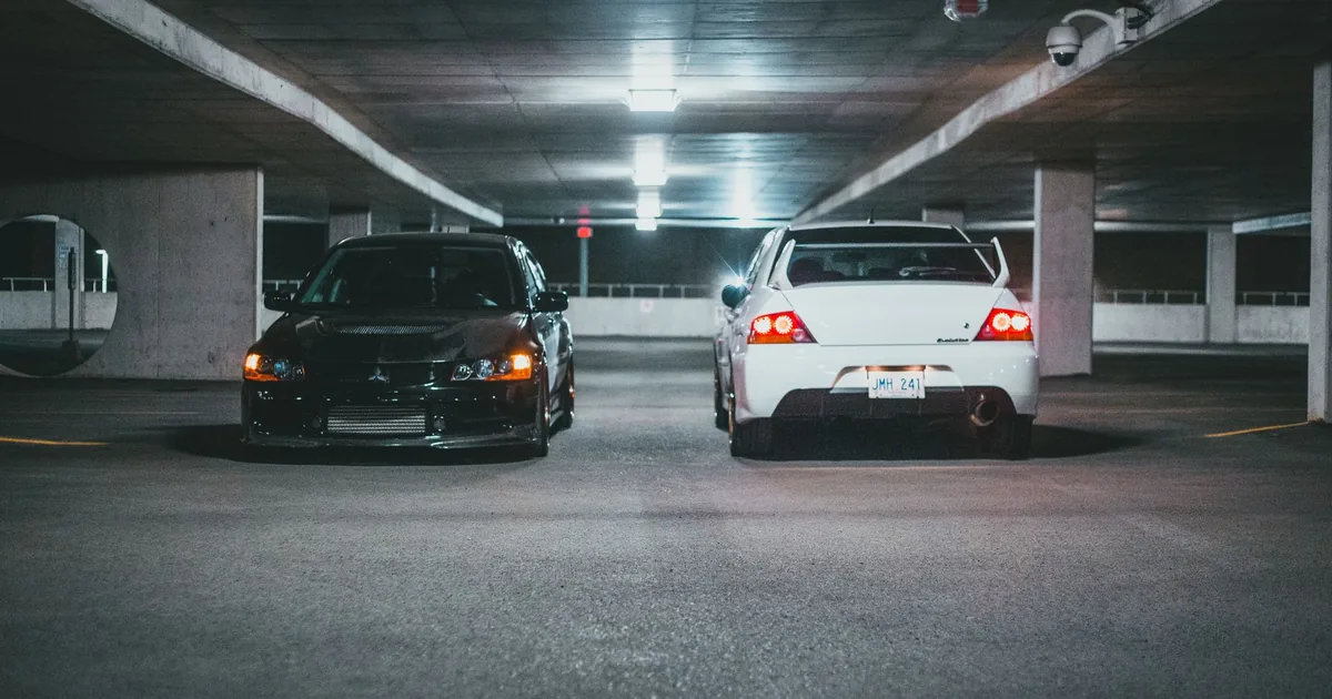Two cars parked in a dimly lit underground parking garage.
