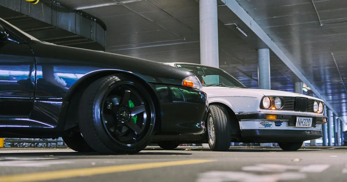 Two cars parked in an underground parking garage with concrete.