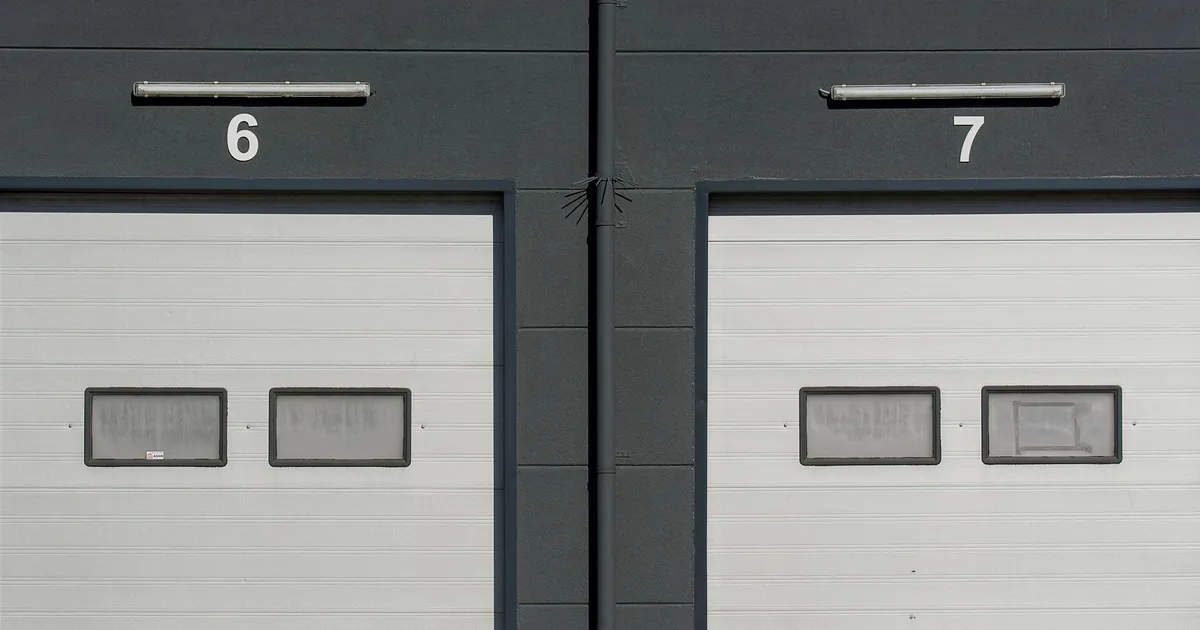 Two garage doors numbered 6 and 7 with windows and a dark wall.