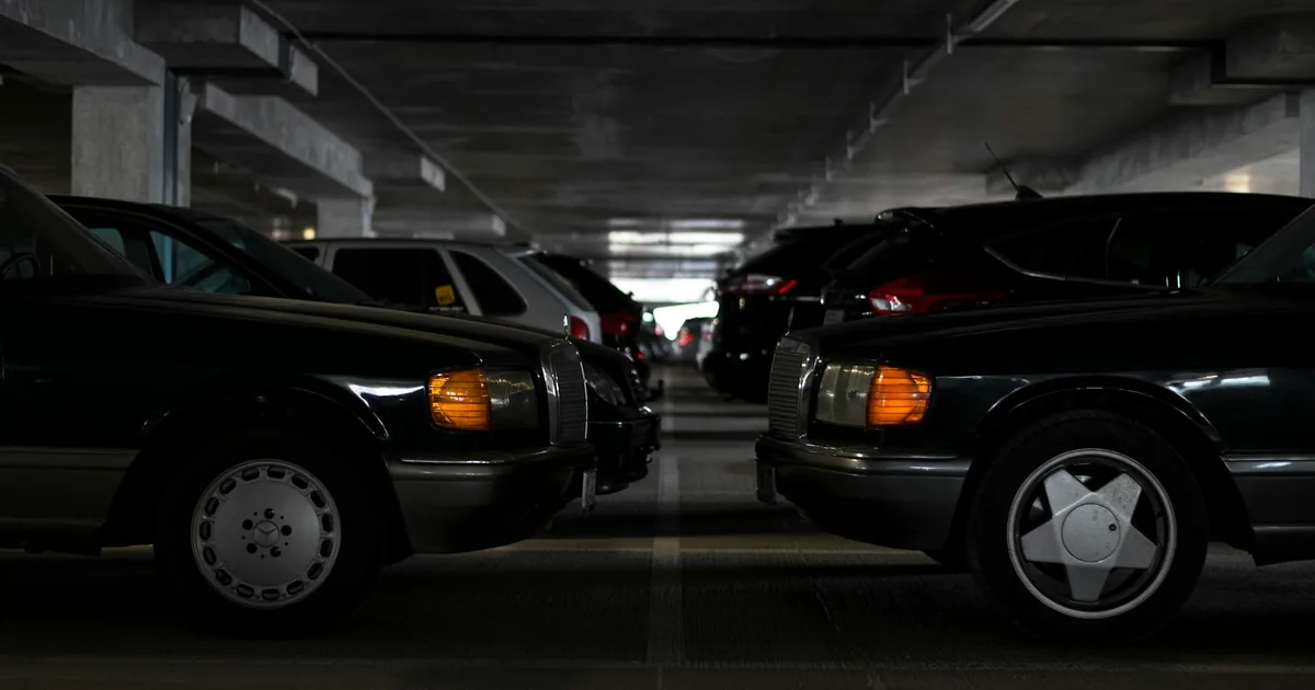 Two parked cars in a dimly lit parking garage with multiple.