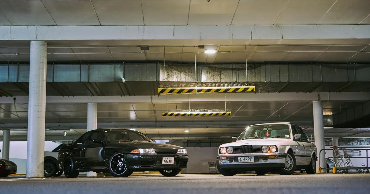 Two parked cars in an indoor parking garage with overhead lighting.