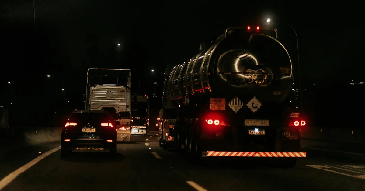 Vehicles parked on a road at night including a large truck and.