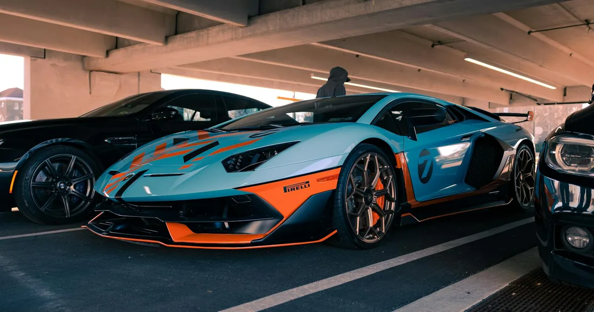 Vibrant sports car parked under a structure with two other vehicles.