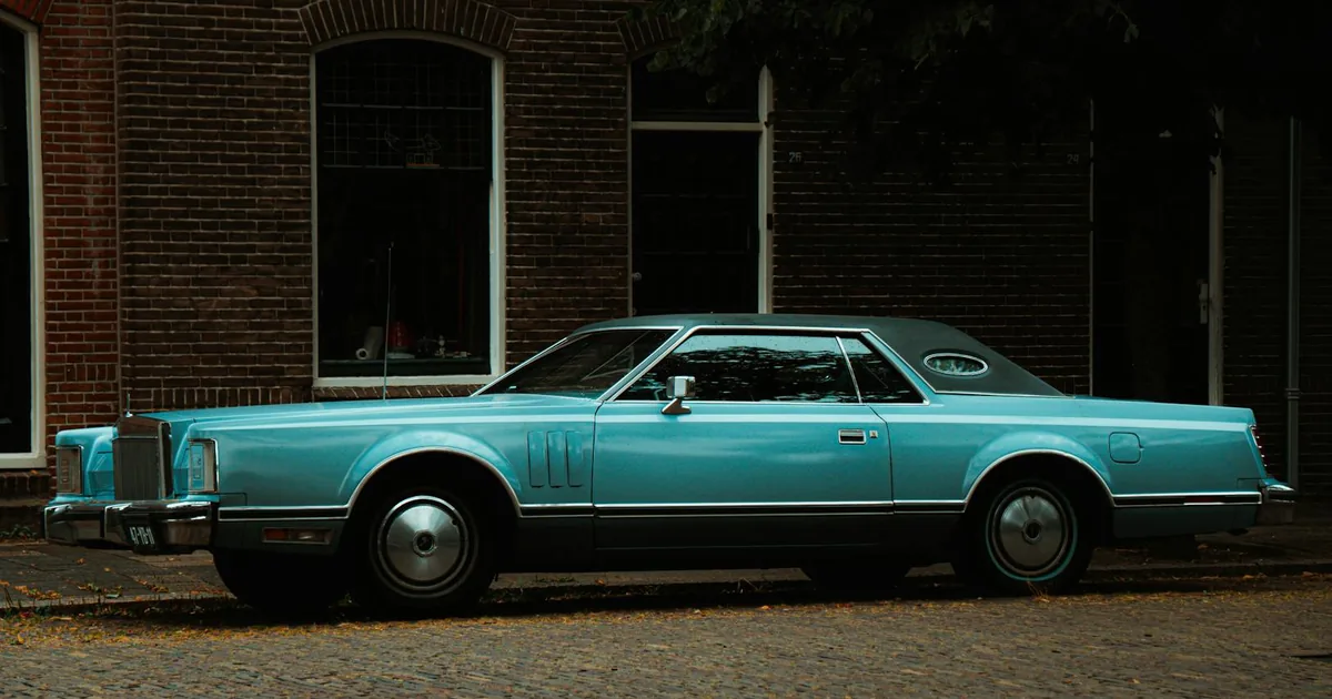 Vintage car parked along a brick lined street near buildings.