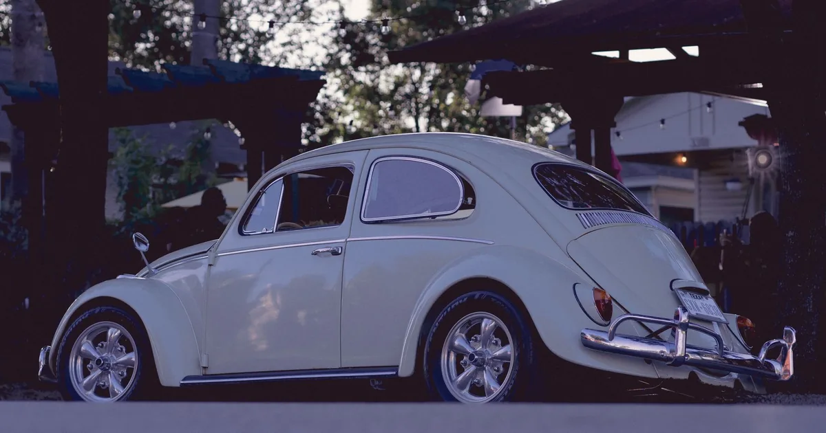 Vintage car parked in a shaded area of a parking lot.