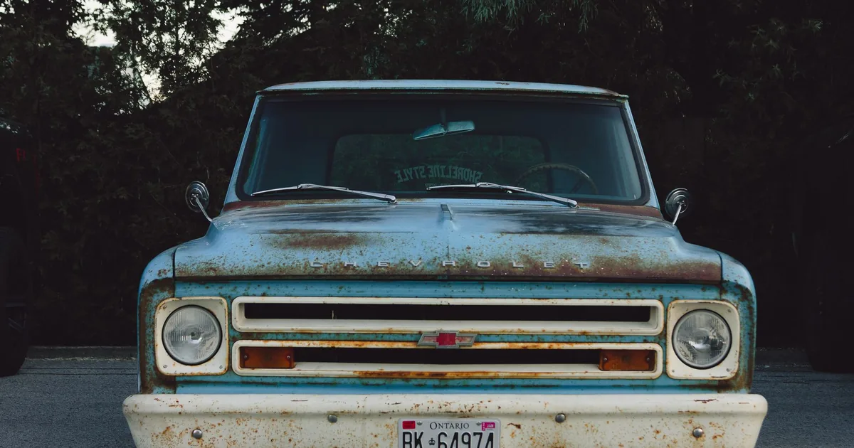 Vintage truck with rust and wear parked in a lot surrounded by.